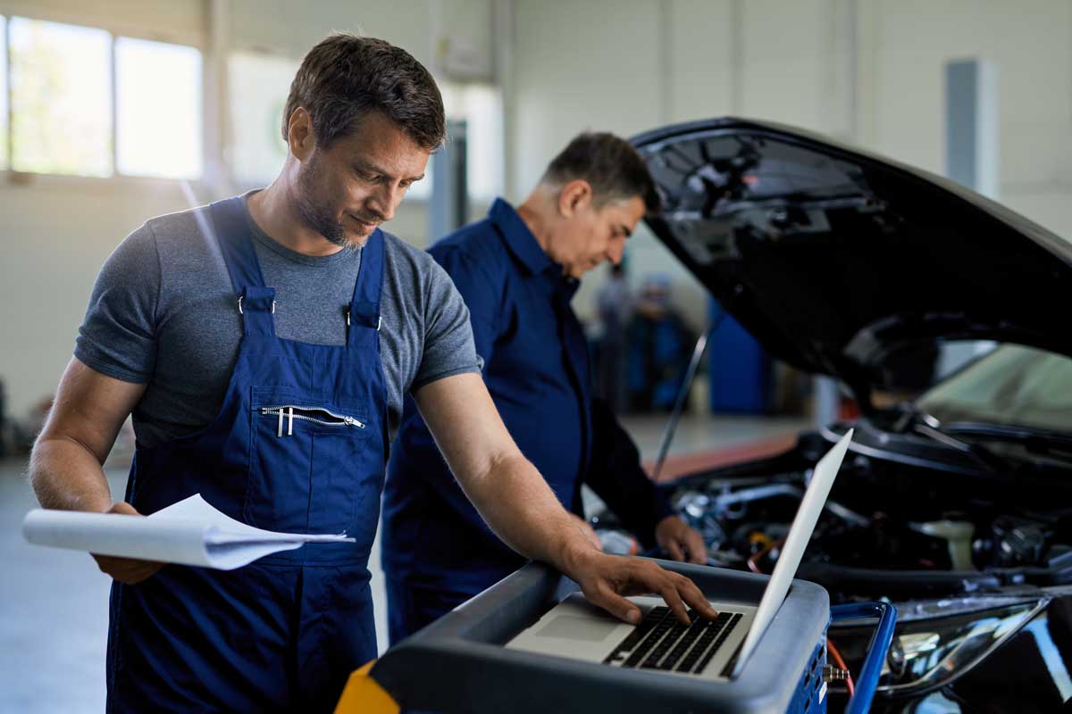 engineer in garage viewing inspection report on laptop